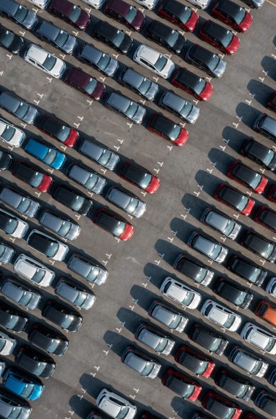 Aerial top view rows of new cars parked in distribution center on car factory.