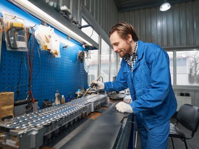 Smiling man inspecting car parts in garage